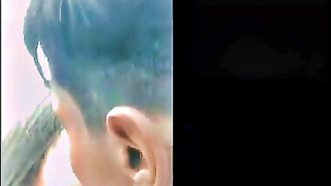 Man with blue undercut hair holding green cucumber near his ear close-up
