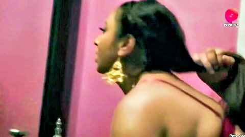 Ebony woman with long braids and gold earrings in red top, side profile view