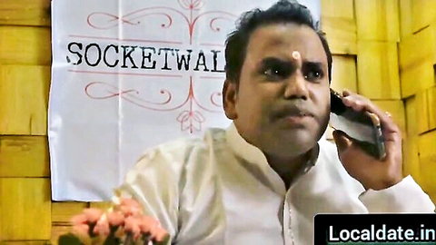 Serious Indian man in white kurta with tilak talking on phone against Socketwall banner