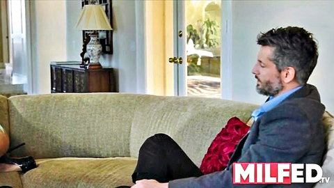 Mature suited man sits on couch in luxurious living room for MILF cuckold scene