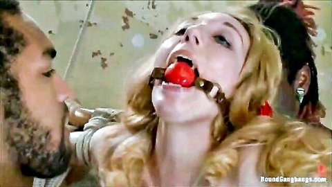Blonde submissive gagged with red ballgag and bound by two black men in intense gangbang BDSM