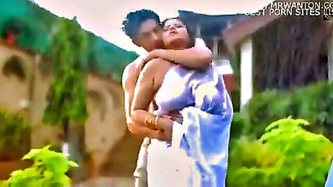 Indian MILF in sheer white saree embraced tightly by shirtless muscular man outdoors in garden