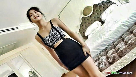 Petite Thai teen smiling in sexy crop top and mini skirt posing teasingly in bedroom