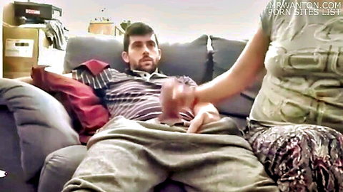 Indian man on couch pants down exposing hard cock gripped by woman's hand