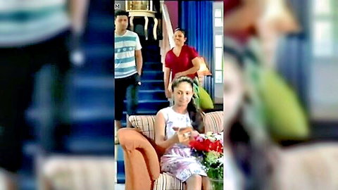 Cute Sri Lankan teen girl in floral dress sits on couch holding phone with family in background