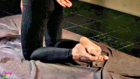 Kneeling woman in black leggings with bare soles up, foot fetish tease