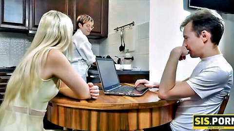 Blonde babe in sheer white top sits with stepbrother at kitchen table on laptop while redhead cooks