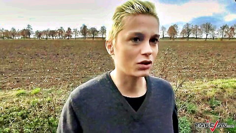Blonde MILF in gray sweater standing in field for TakeVan van pickup