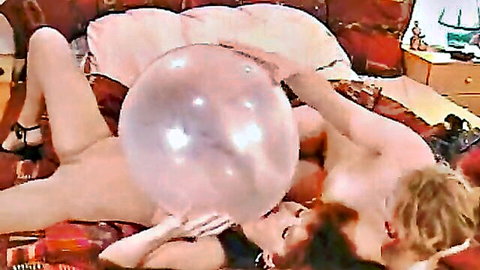 Nude redhead in heels spreads legs holding giant balloon on pussy while kissing naked guy on bed