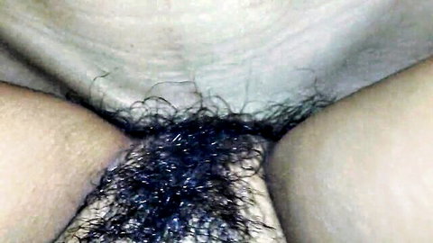 Close-up of woman's hairy pubic area with spread thighs