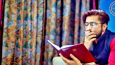 Thoughtful Indian man in glasses reading book while smoking