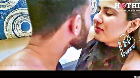 Desi couple in passionate close-up kiss, woman in black dress with blue earrings