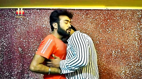 Two Indian men embracing intimately, bearded guy in red shirt hugging striped shirt man