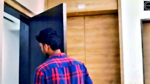 Indian man in plaid shirt standing at open bedroom door teasing entry