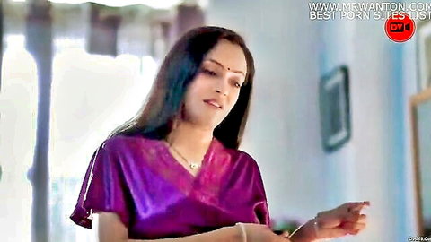 Sexy Indian mature babe in shiny purple satin top smiling seductively with cleavage