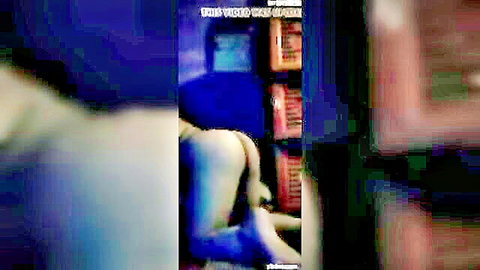 Busty woman bends over showing huge bare ass and pussy crack in blue-lit room with shelves