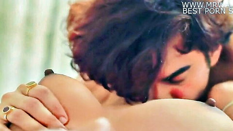 Indian man kissing exposed breast of nude woman in intimate embrace
