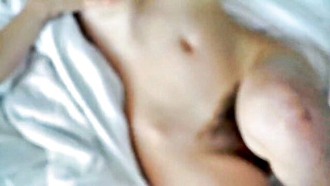 Blurry closeup of sexy hairy man's nude torso lounging on white sheets