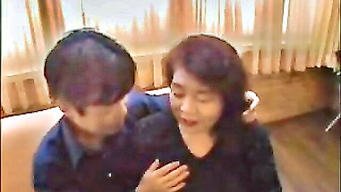 Mature Japanese couple intimately embracing and kissing passionately in bedroom