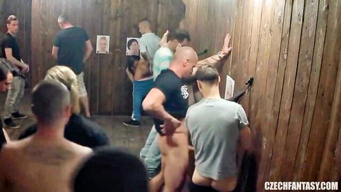 Petite naked woman surrounded by men with cocks out in crowded Czech gloryhole booth