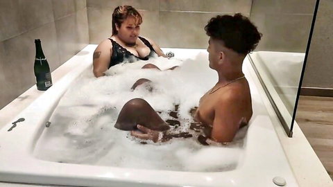 Curvy BBW mature black babe with big tits in black bikini top cuddles muscular black stud in steamy bubble bath tub