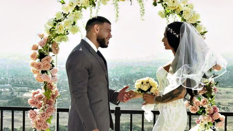 Eva Maxim in wedding dress with Ricky Larkin under floral arch in Trans Brides