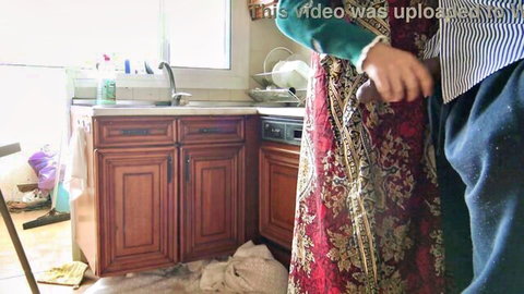 Turkish stepmom in floral dress gripped from behind in kitchen