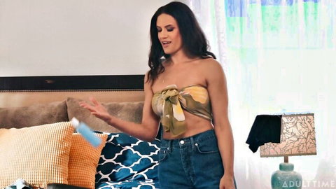 Brunette MILF in tied crop top and jeans holds blue masturbator sleeve toy seductively
