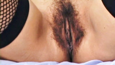 Closeup of woman's hairy bushy pussy spread wide open in black fishnet lingerie