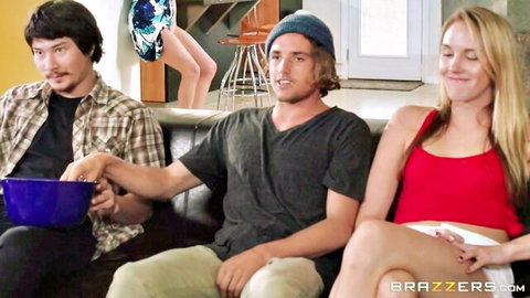 Busty blonde spreads legs wide teasing two guys holding popcorn on couch