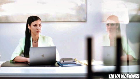 Curvy olive-skinned brunette in tight green suit sits at office desk with MacBook, big tits and ponytail teasing