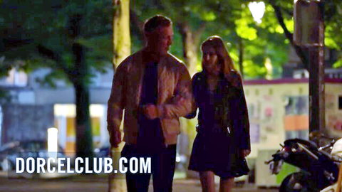 Sexy blonde babe in short skirt walks hand-in-hand with handsome man on romantic night street