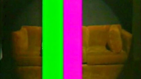 Empty vintage yellow couch in dark room with green and pink chroma key bars