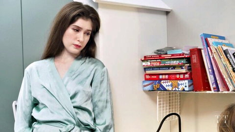 Melancholic brunette in silky green robe showing cleavage by bookshelf