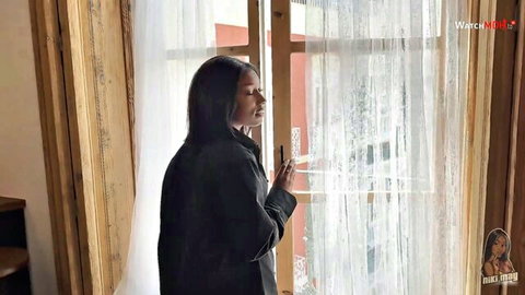 Nikimay in seductive black coat by window, small tits domination tease