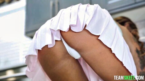 Charlotte Mae bends over in white pleated skirt, teasing ass and panties