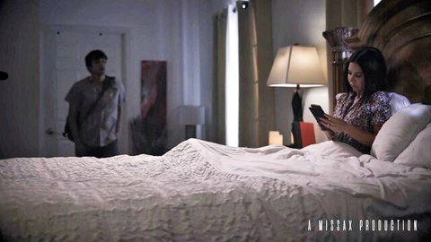 Brooke Barclays as horny MILF in bed, watching porn on phone with man in background