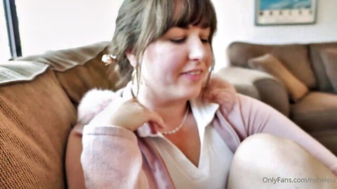 Leia Lovelyn smiling in pink cardigan and open blouse on couch