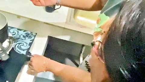 Asian stepsister in green top pouring drink in kitchen with stepbrother