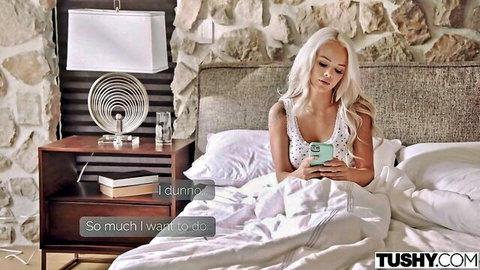 Blonde petite Elsa Jean in lingerie on bed checking phone