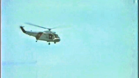 Vintage military helicopter flying over blue sky in retro footage
