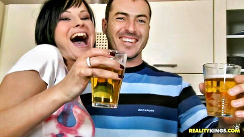 Abbie Cat and Nick Lang toasting beers, laughing in hot Euro sex party