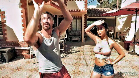 Jade Kush in crop top and shorts poses with athletic man holding basketball outdoors