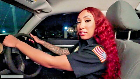 Jade in sexy police uniform driving car at night, red hair and tattoos