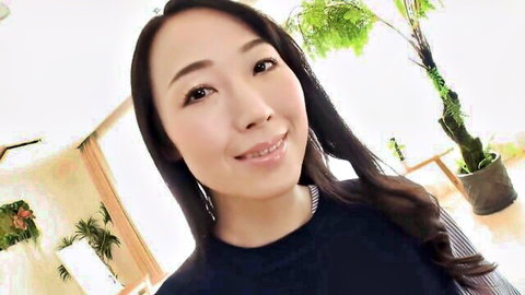 Smiling sexy Asian wife in black top teases with tempting gaze