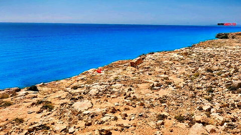 Scenic view of vast blue ocean and rocky cliffs under clear sky