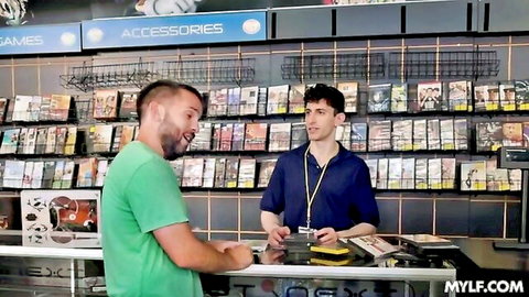 Two fit guys at game store counter, flirty vibe