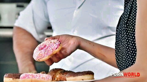Hand holding pink sprinkled donut in kitchen with Pornworld watermark teasing food play