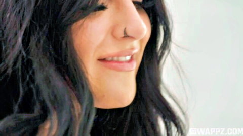 Serena Sterling smiling close-up with nose and lip piercings, black wavy hair
