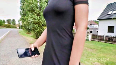 Brunette in tight black dress flaunting perky tits and hard nipples holding phone outdoors